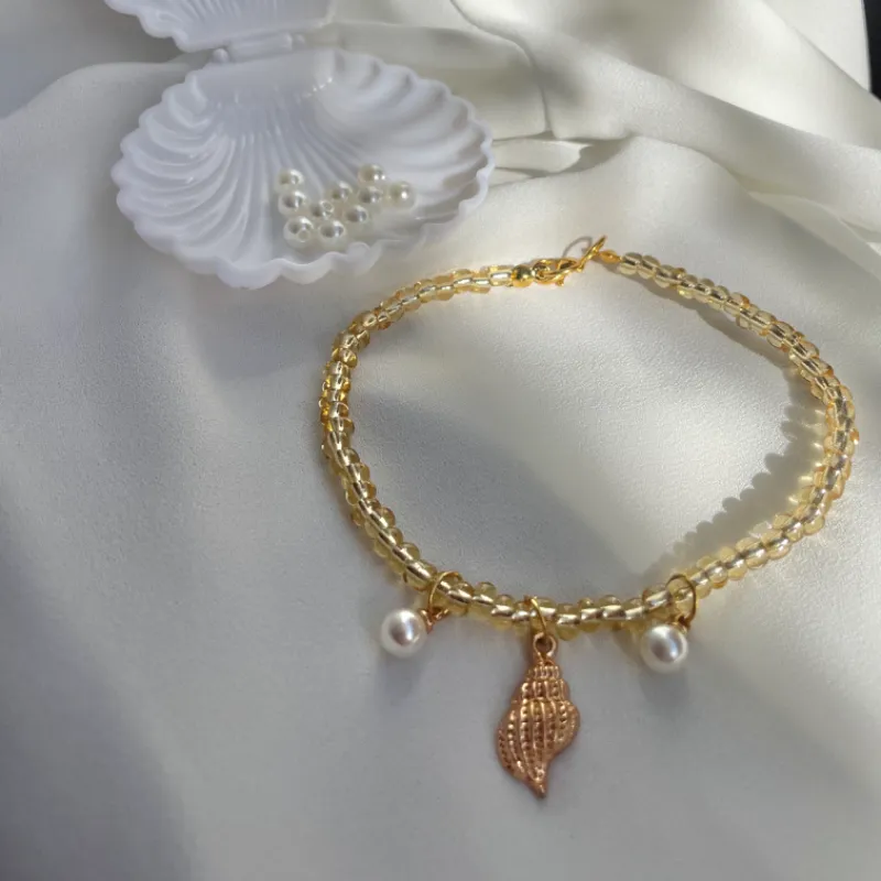 Tobillera de cuentas doradas con dijes