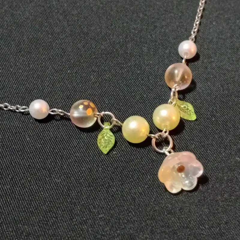 Cadena de flor con hojas y cuentas