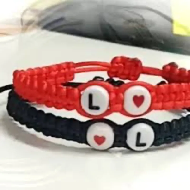 Pareja de pulsos con iniciales y corazón rojo