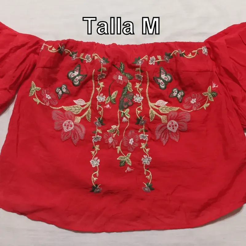 Blusa de mangas roja con flores tejidas.