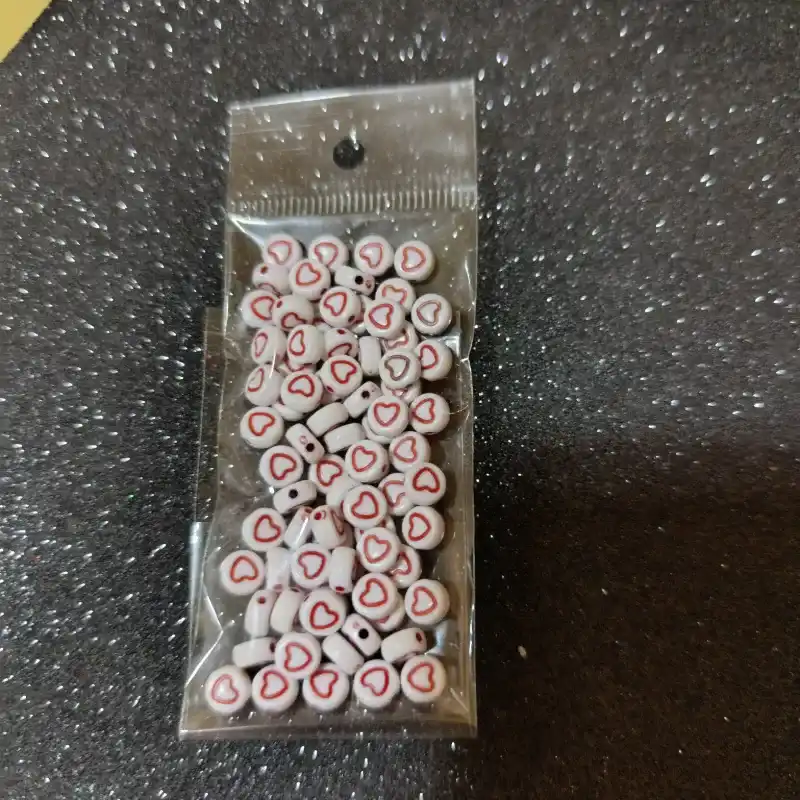 Cuentas plásticas con fondo blanco y corazones rojos