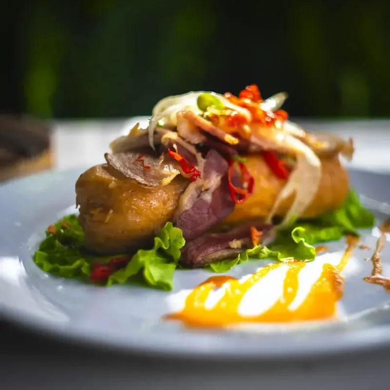 TAMAL CON CARNE, PIMIENTO, CEBOLLA Y BACON CRUJIENTE.